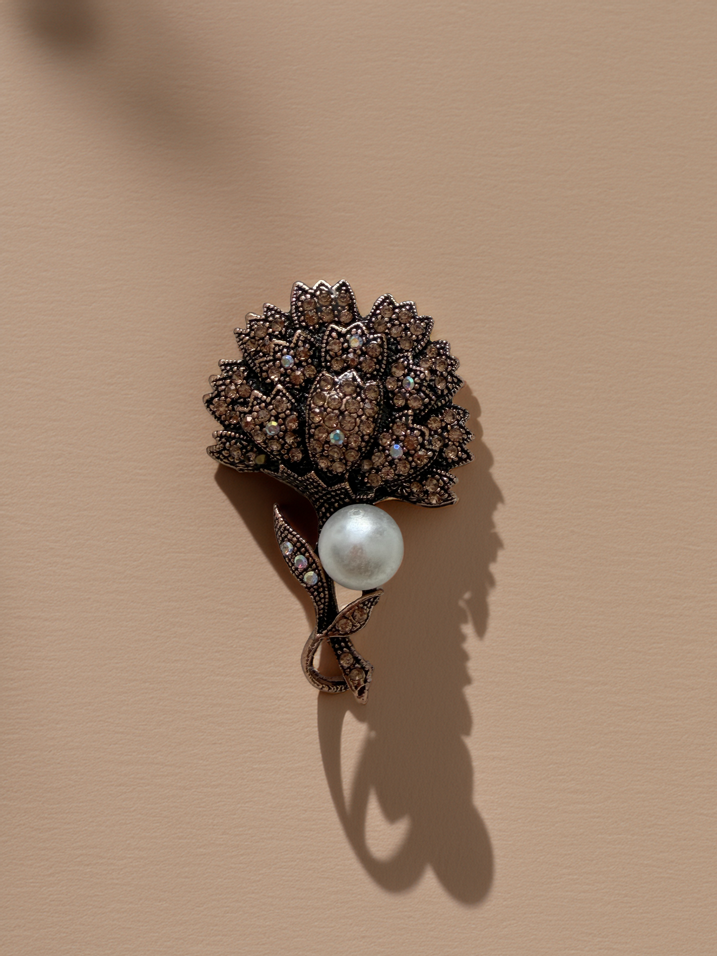 Decorative brooch with a pearl on a beige background