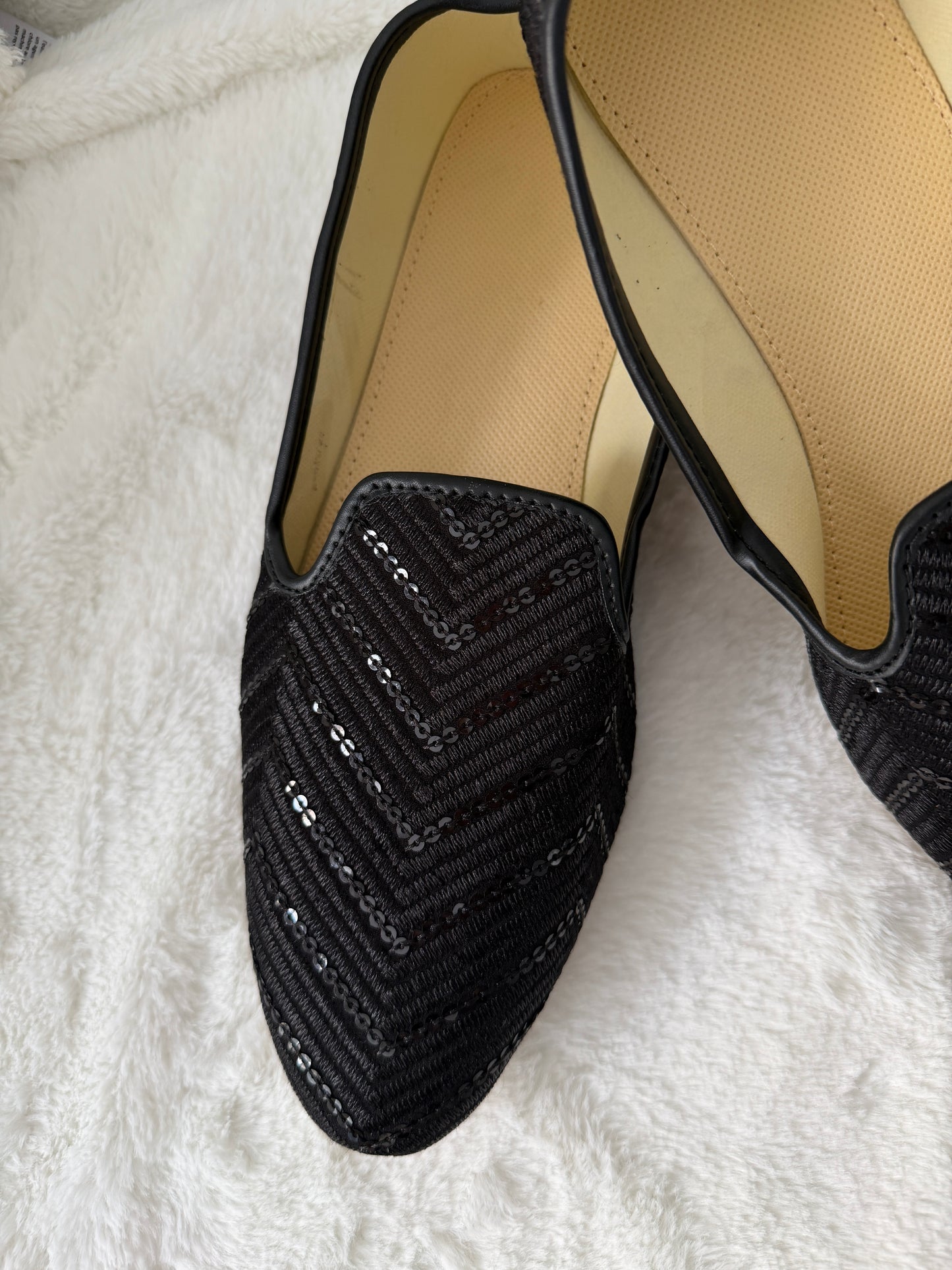 Black sequin flat jutti on a white fluffy surface