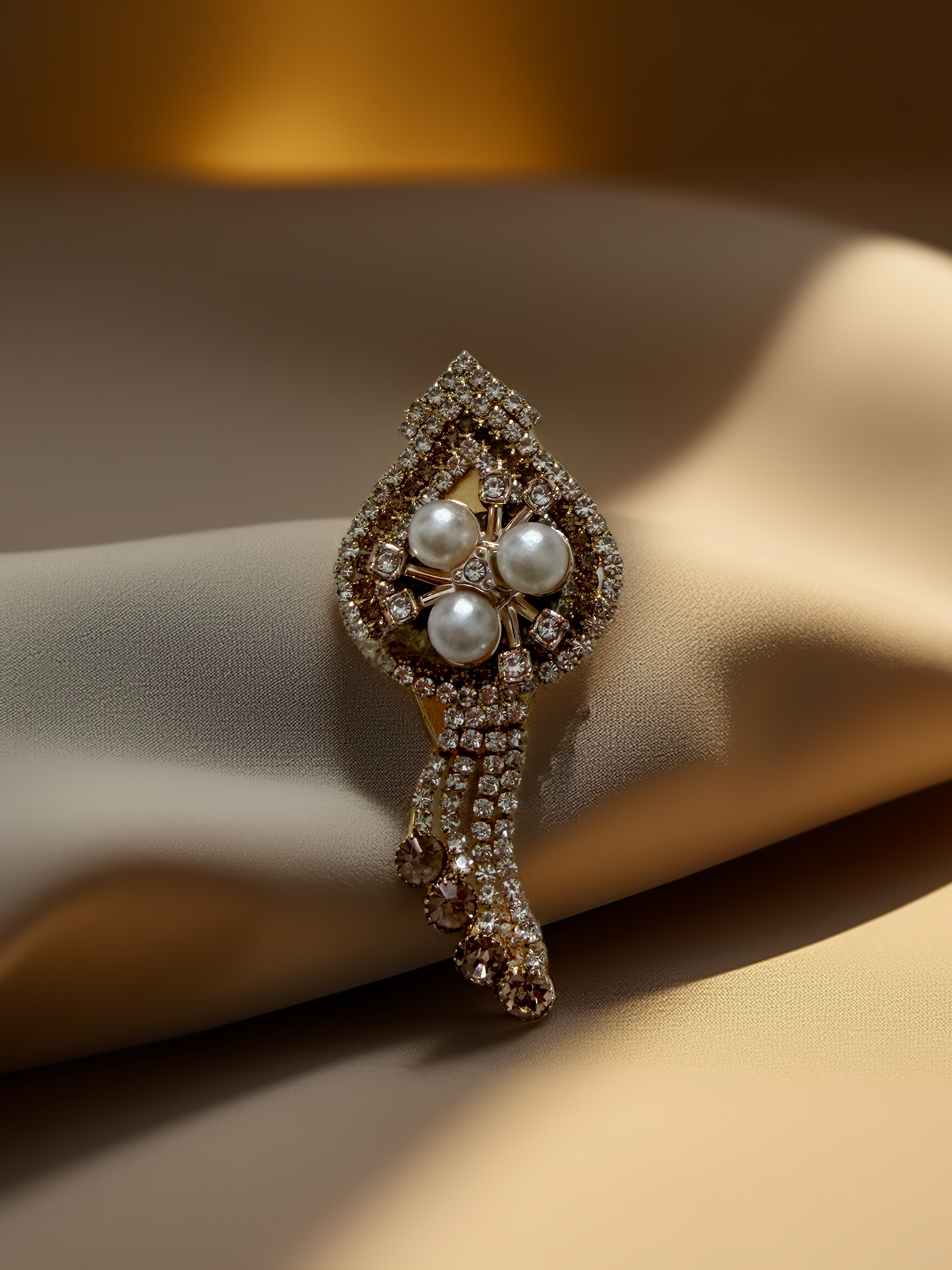 Decorative brooch with pearls and gemstones on a beige fabric background