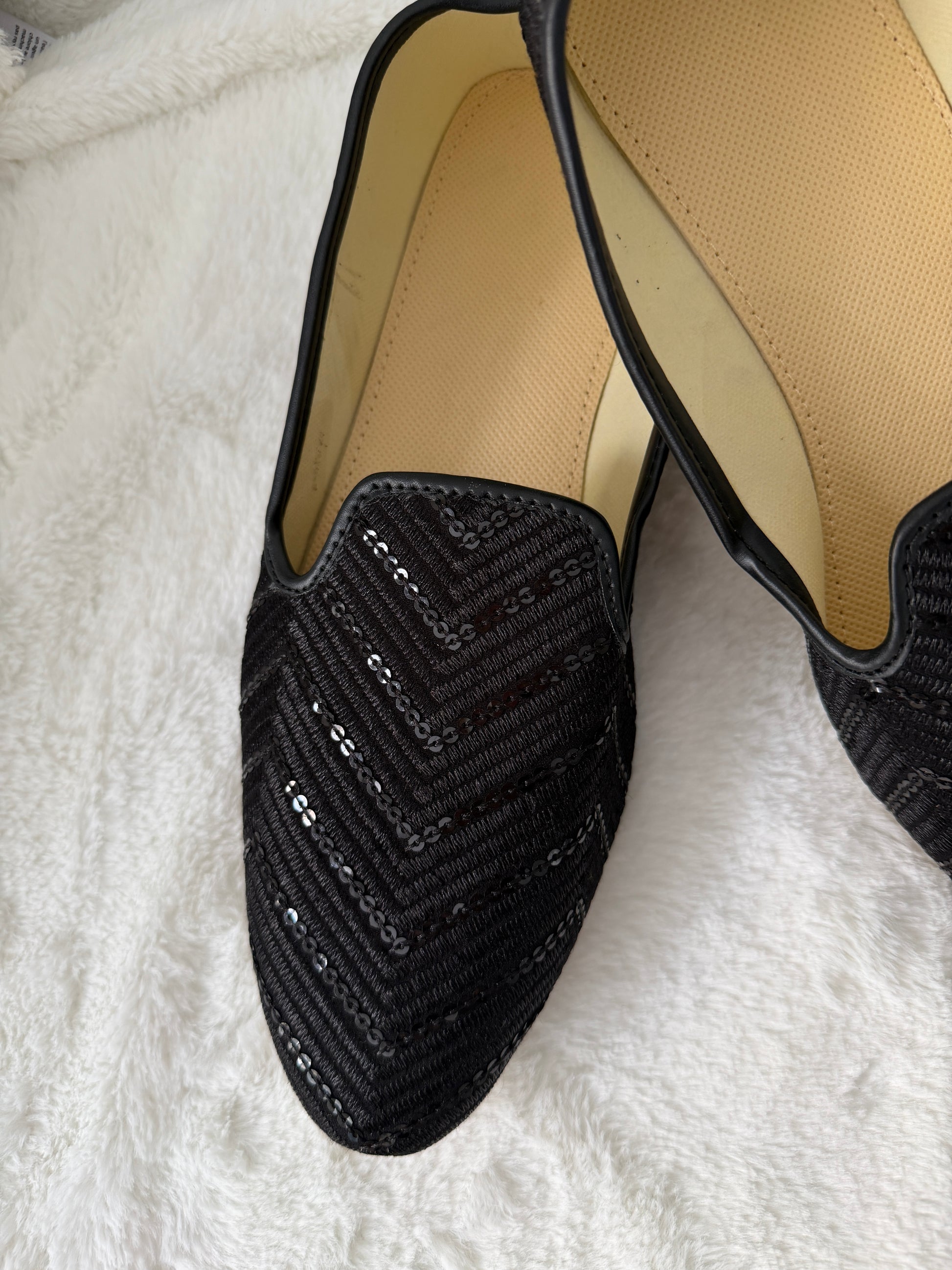 Black sequin flat jutti on a white fluffy surface