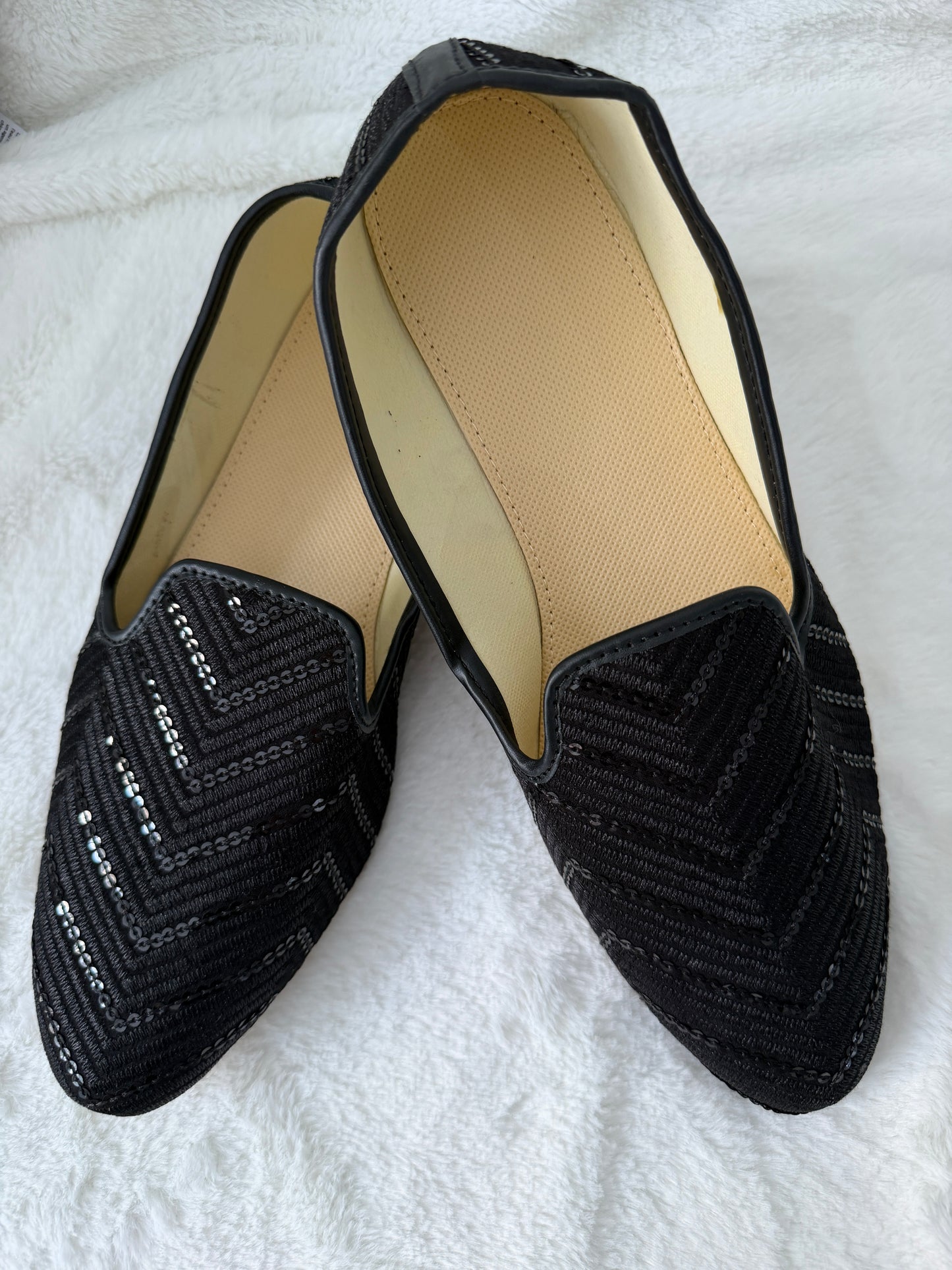 Black Jutti with textured pattern on a white surface