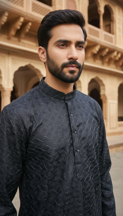 Man wearing a dark patterned kurta standing in front of an architectural background