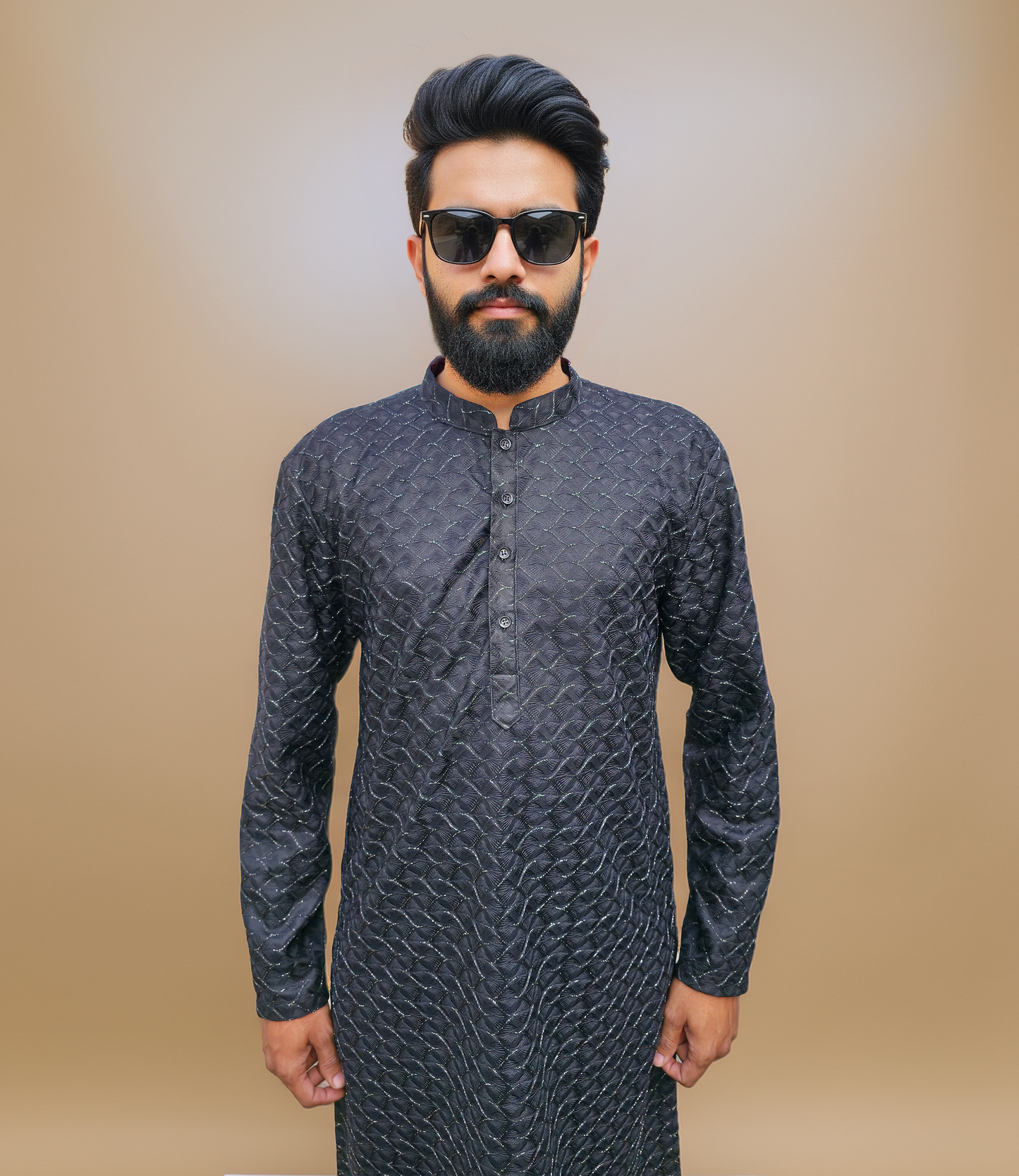 Man wearing a dark patterned kurta against a beige background