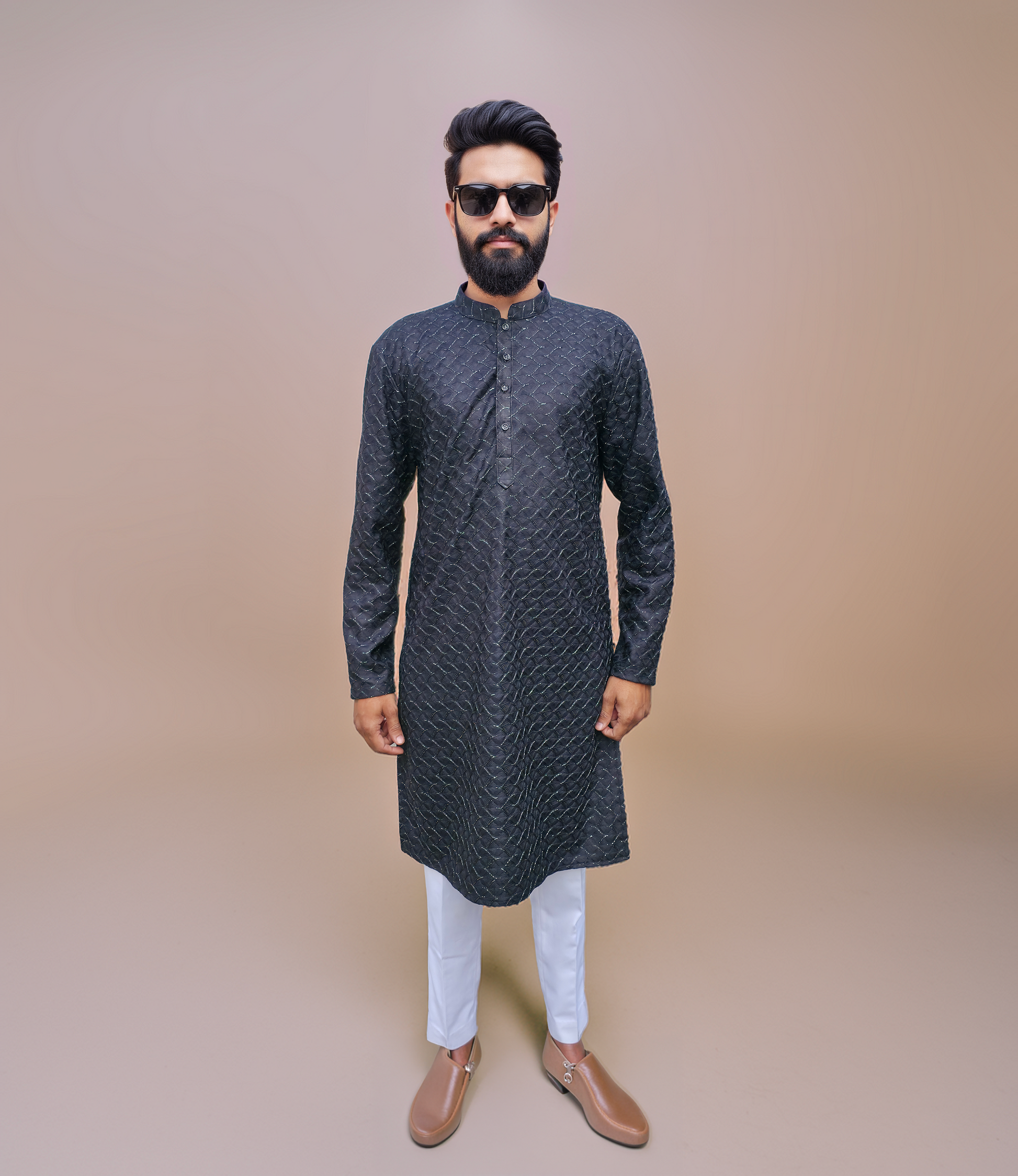 Man wearing a dark patterned kurta with metallic shine with white pants on a beige background