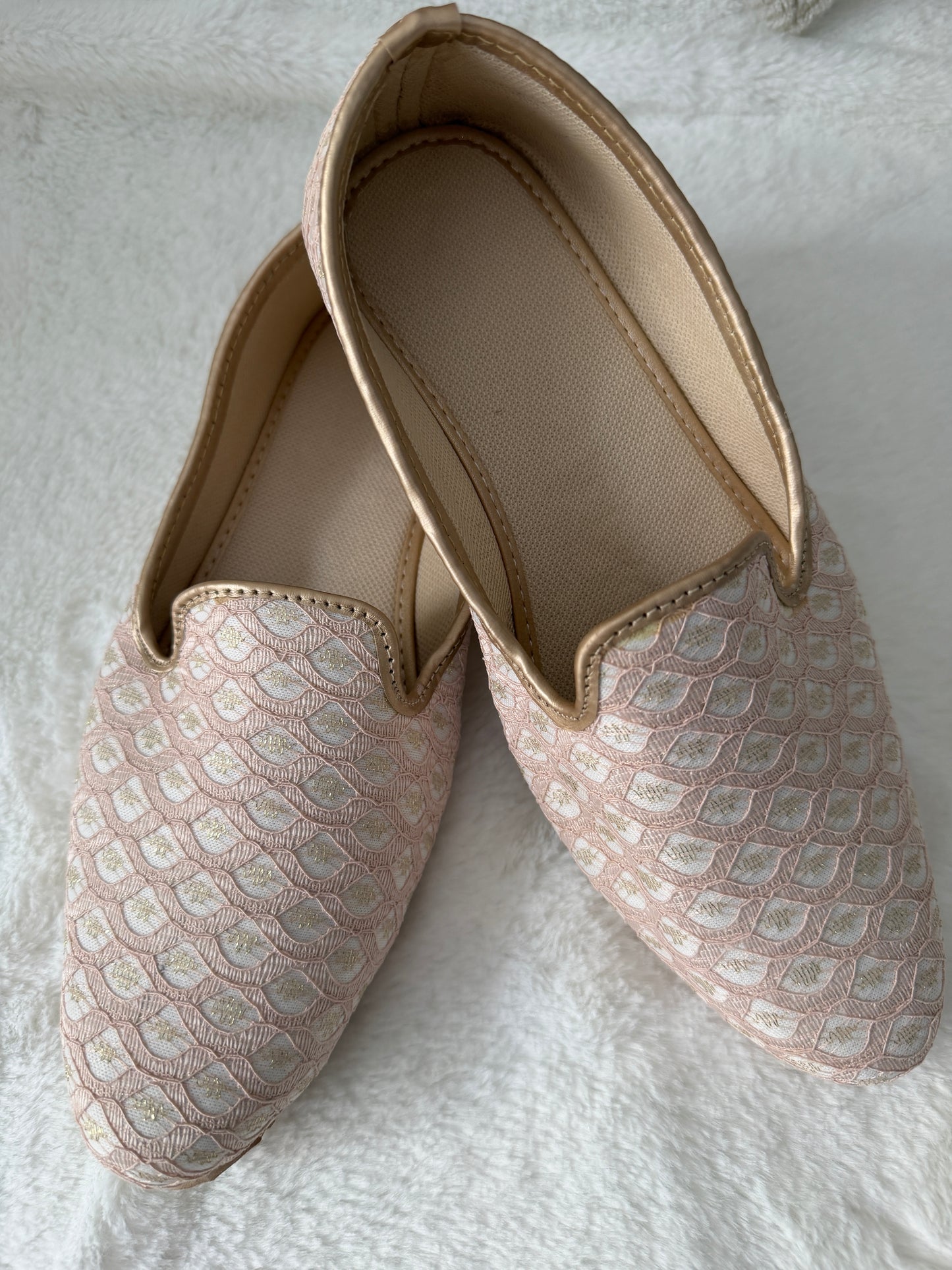 Pair of patterned jutti on a textured white surface