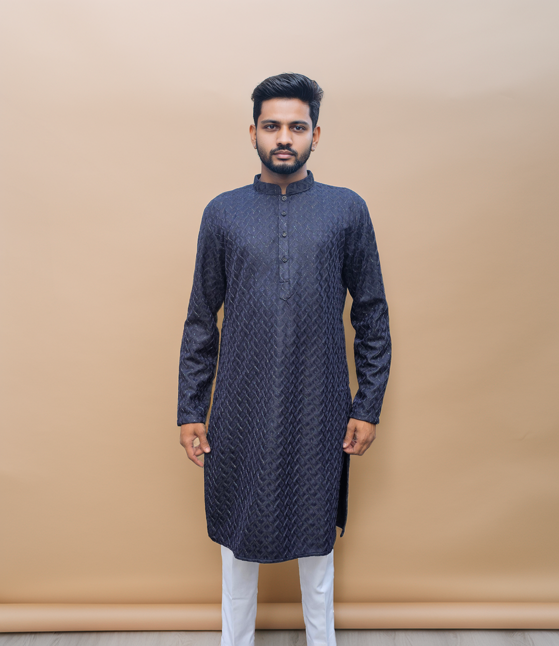 Man wearing a dark blue kurta with white pants against a beige background