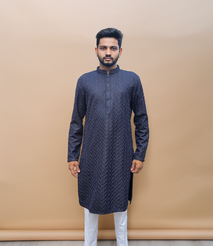 Man wearing a dark blue kurta with white pants against a beige background