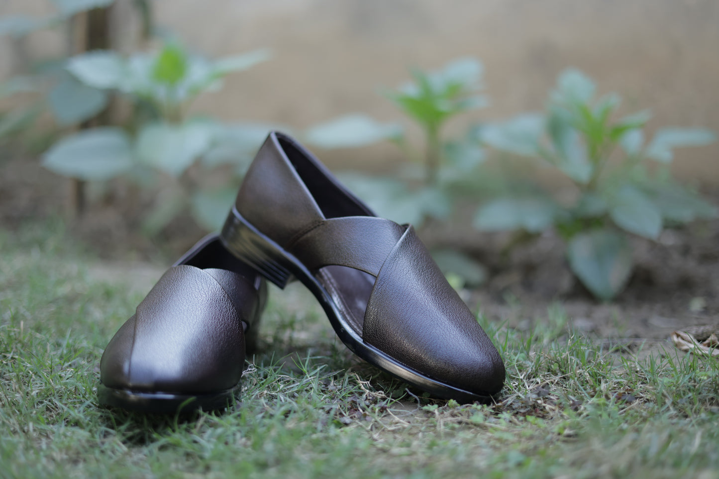 Pair of black shoes on grass with a blurred natural background