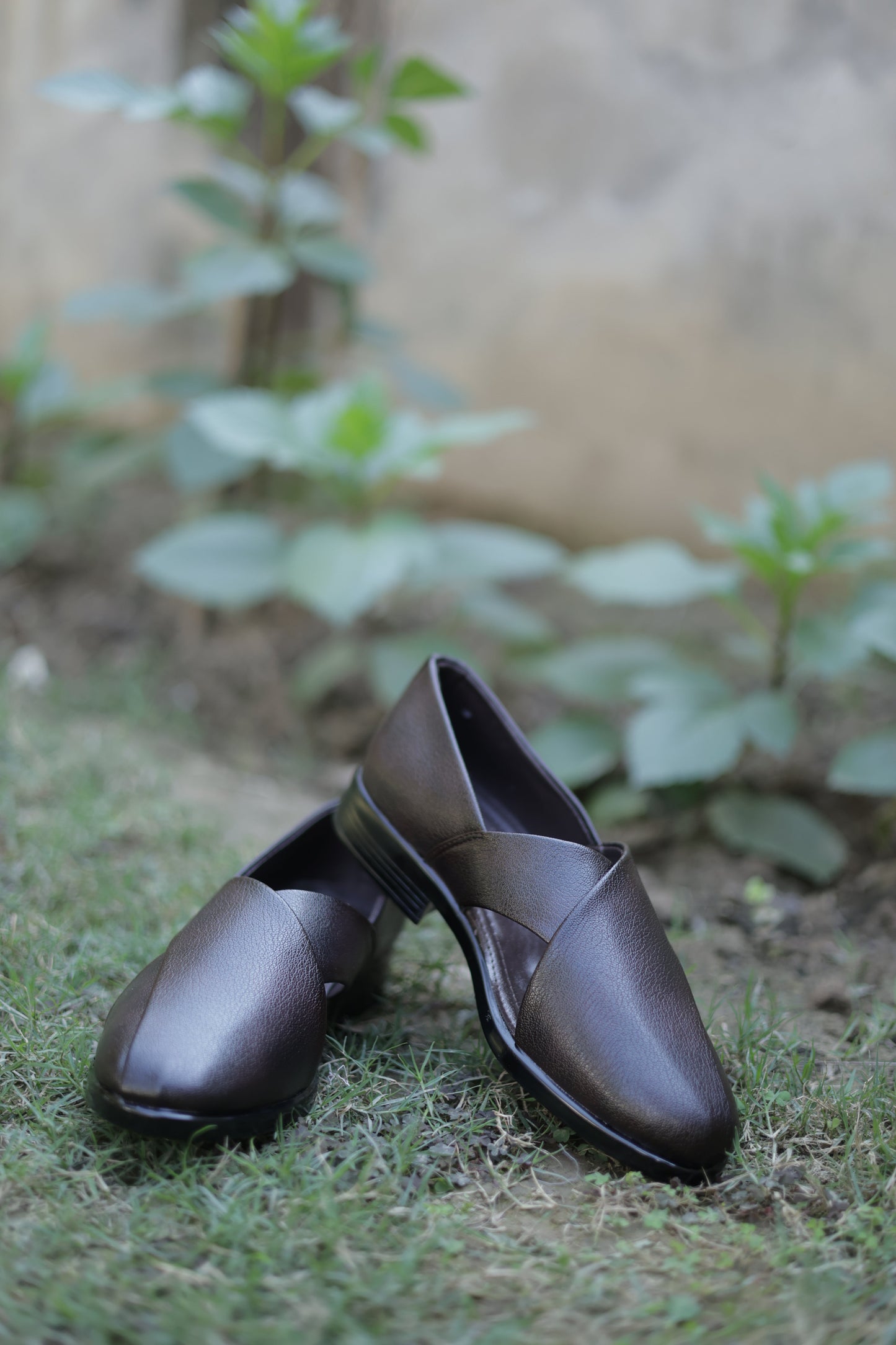 Pair of black shoes on a grassy surface with a blurred natural background