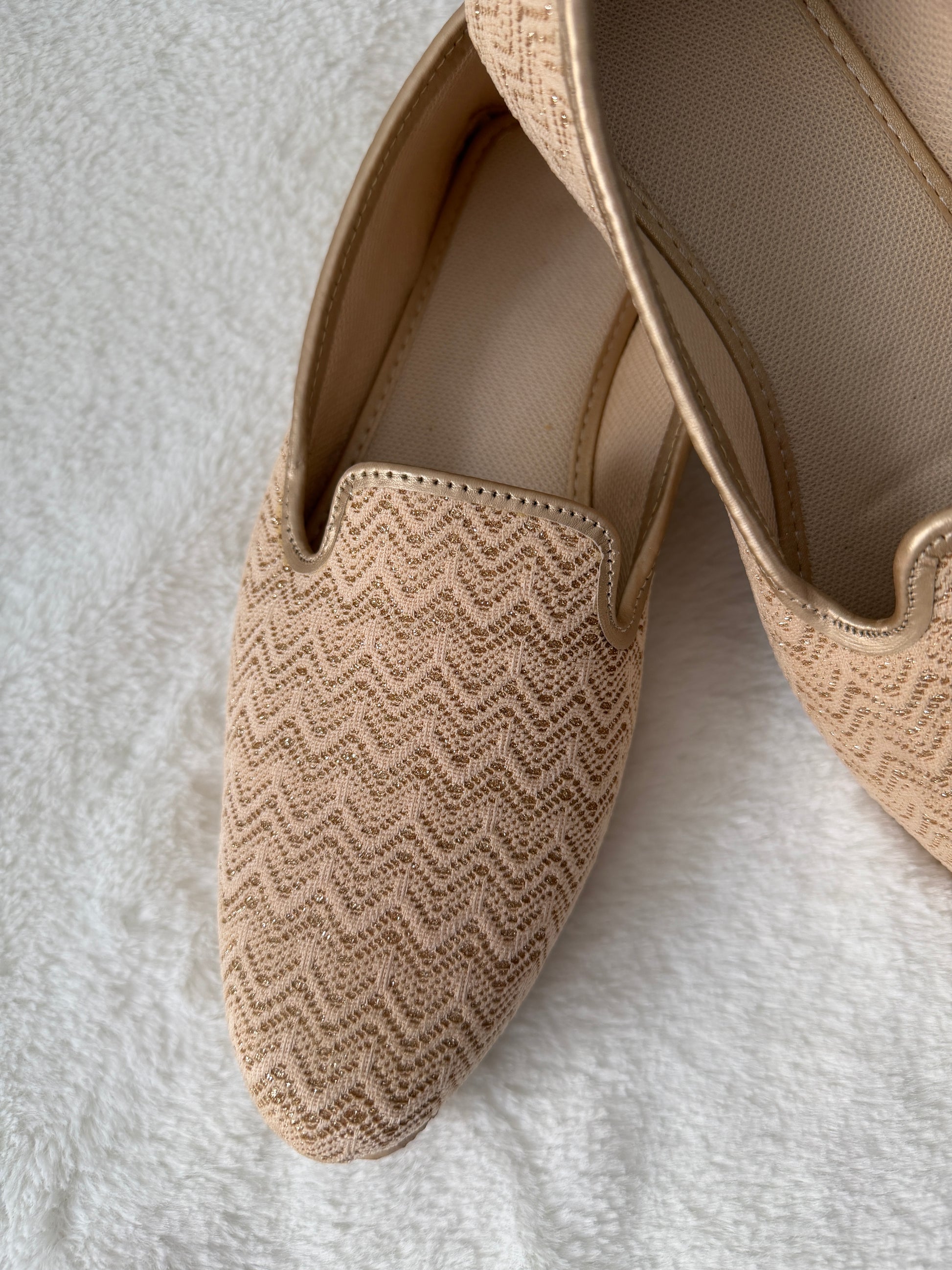 Pair of beige loafers with a textured pattern on a white surface