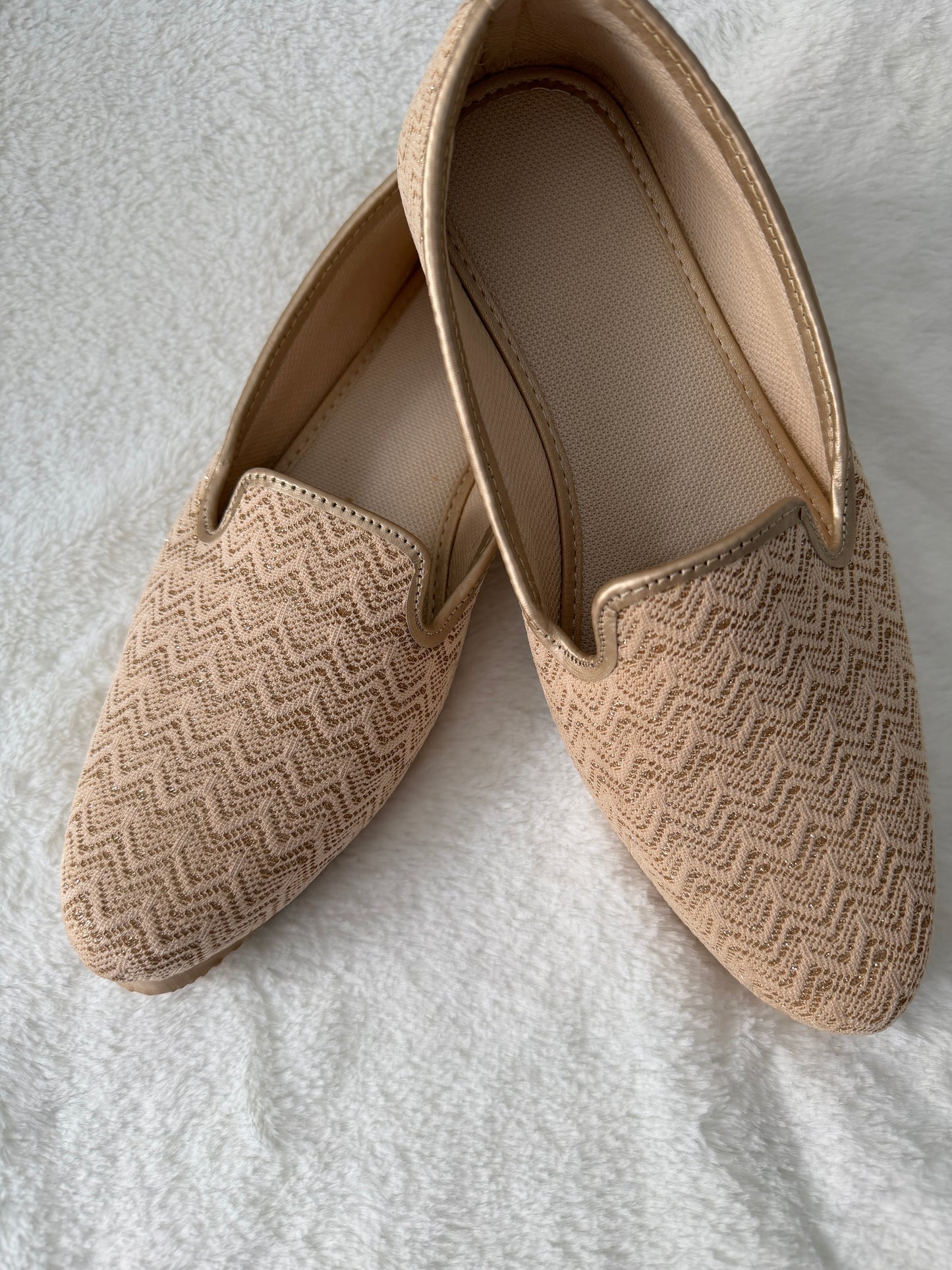 Pair of beige patterned loafers on a light gray background