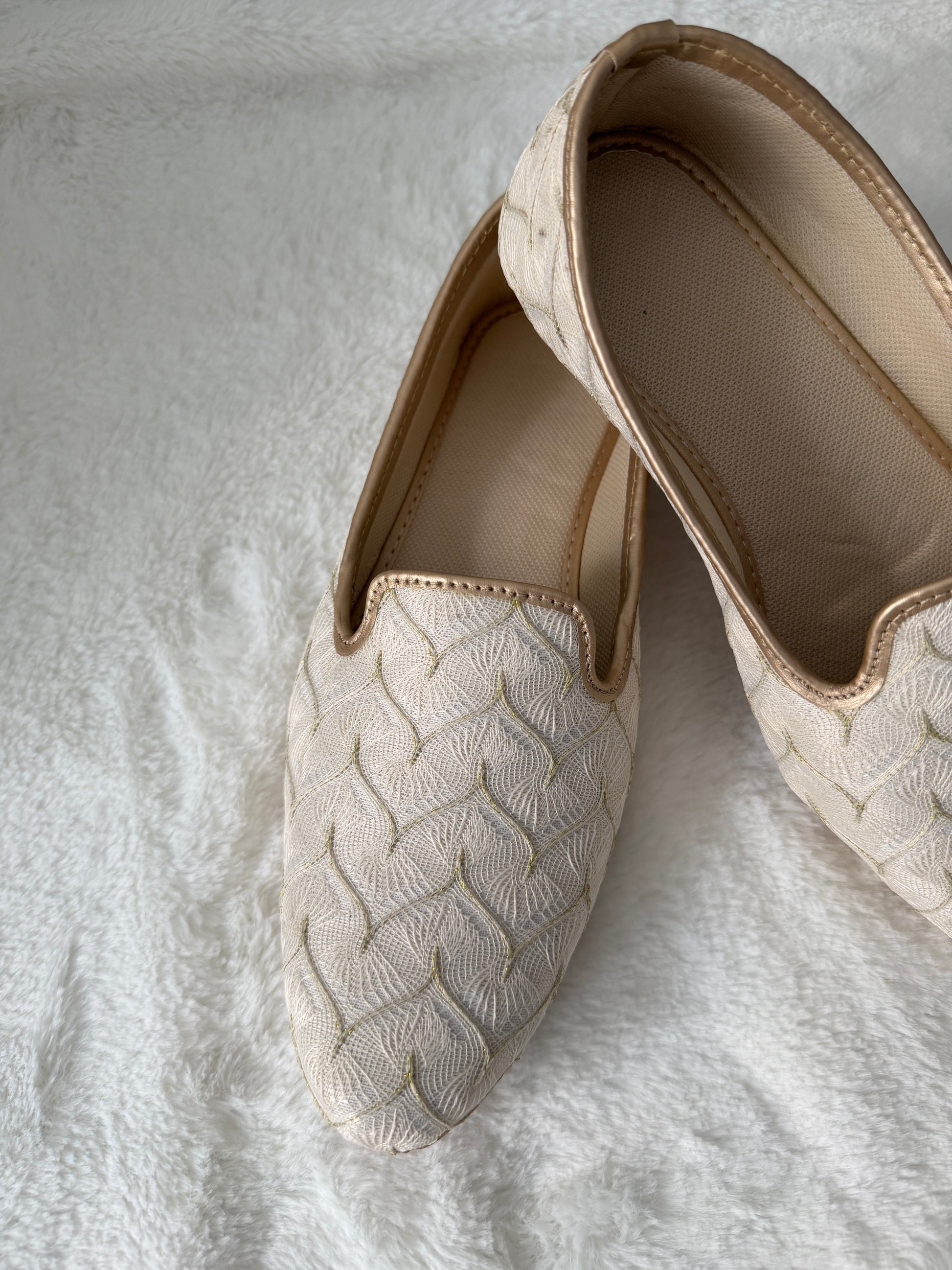 Pair of beige espadrilles on a textured white surface