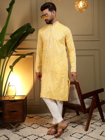 Man wearing a yellow kurta with white pants in an indoor setting.