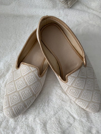 Ivory jutti with textured surface on a white textured background