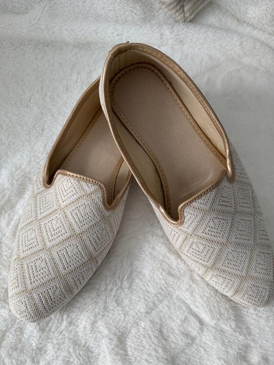 Ivory jutti with textured surface on a white textured background