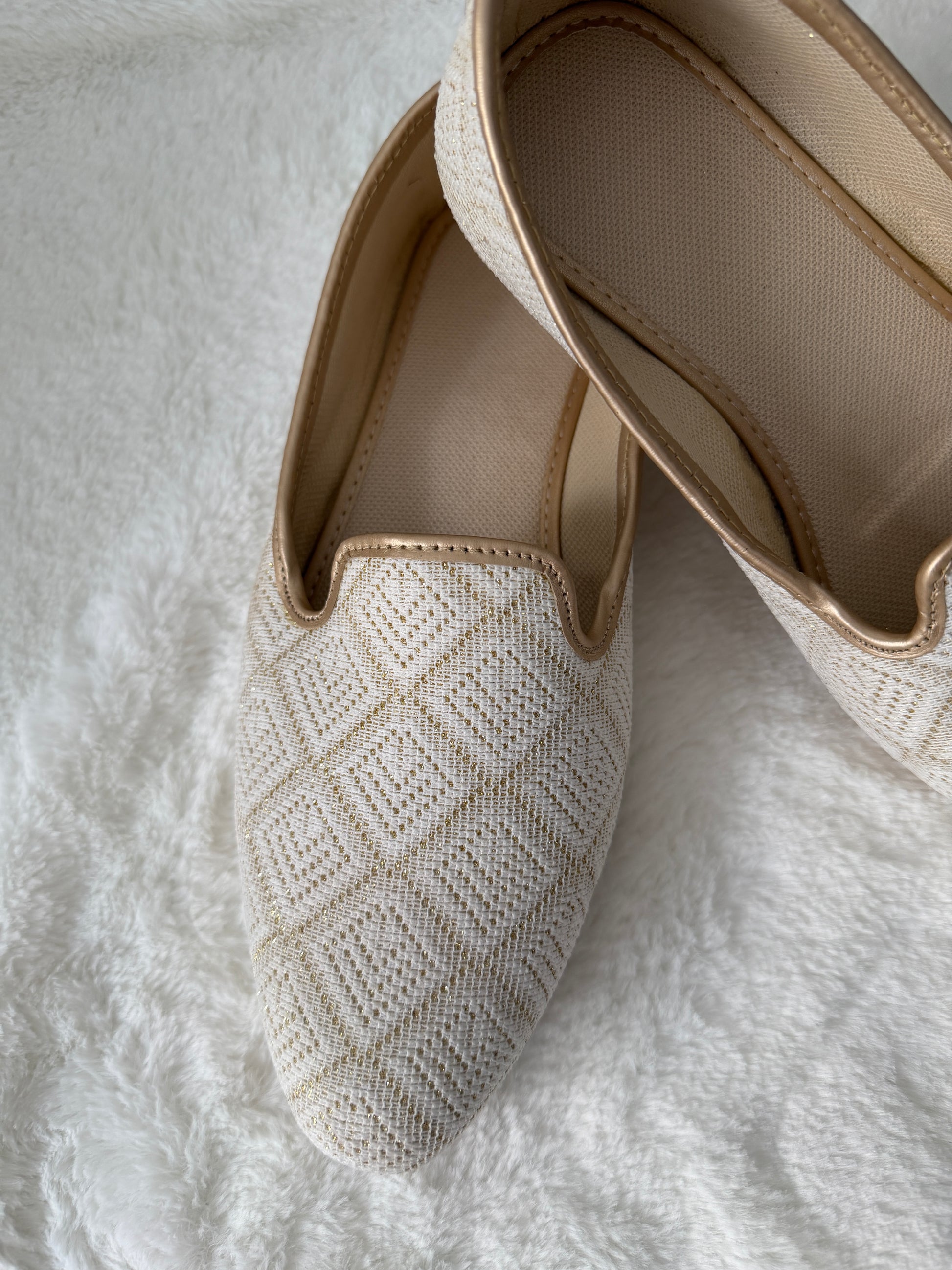 Pair of Ivory woven jutti on a textured white surface
