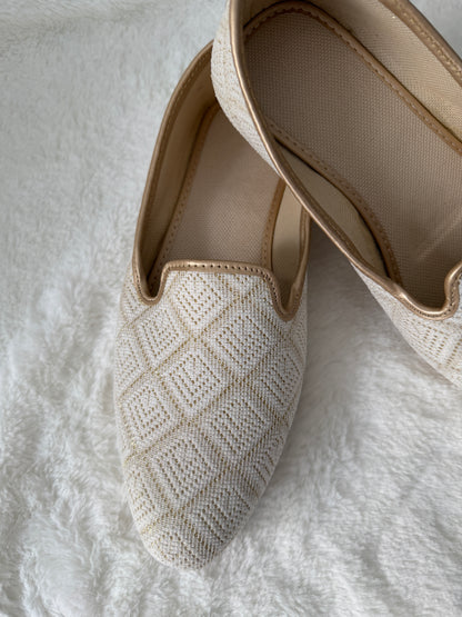 Pair of Ivory woven jutti on a textured white surface