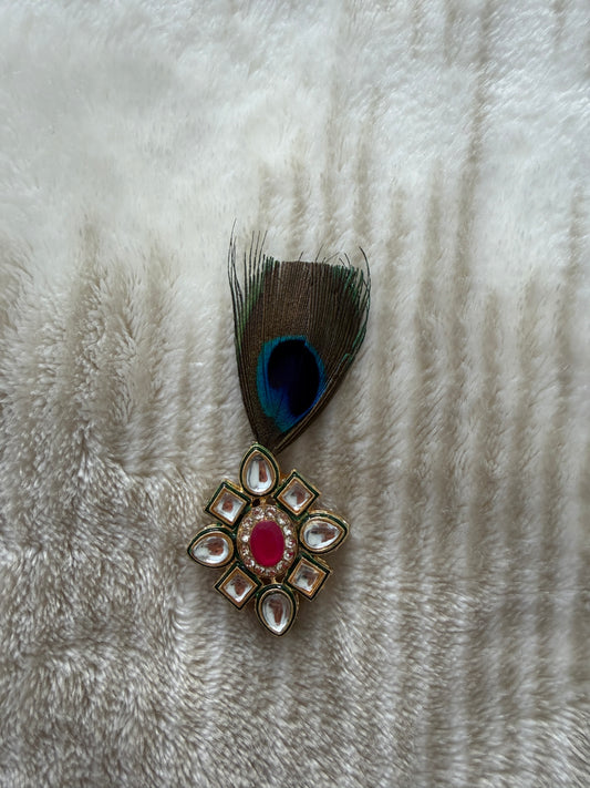 Decorative brooch with peacock feather on a textured white surface