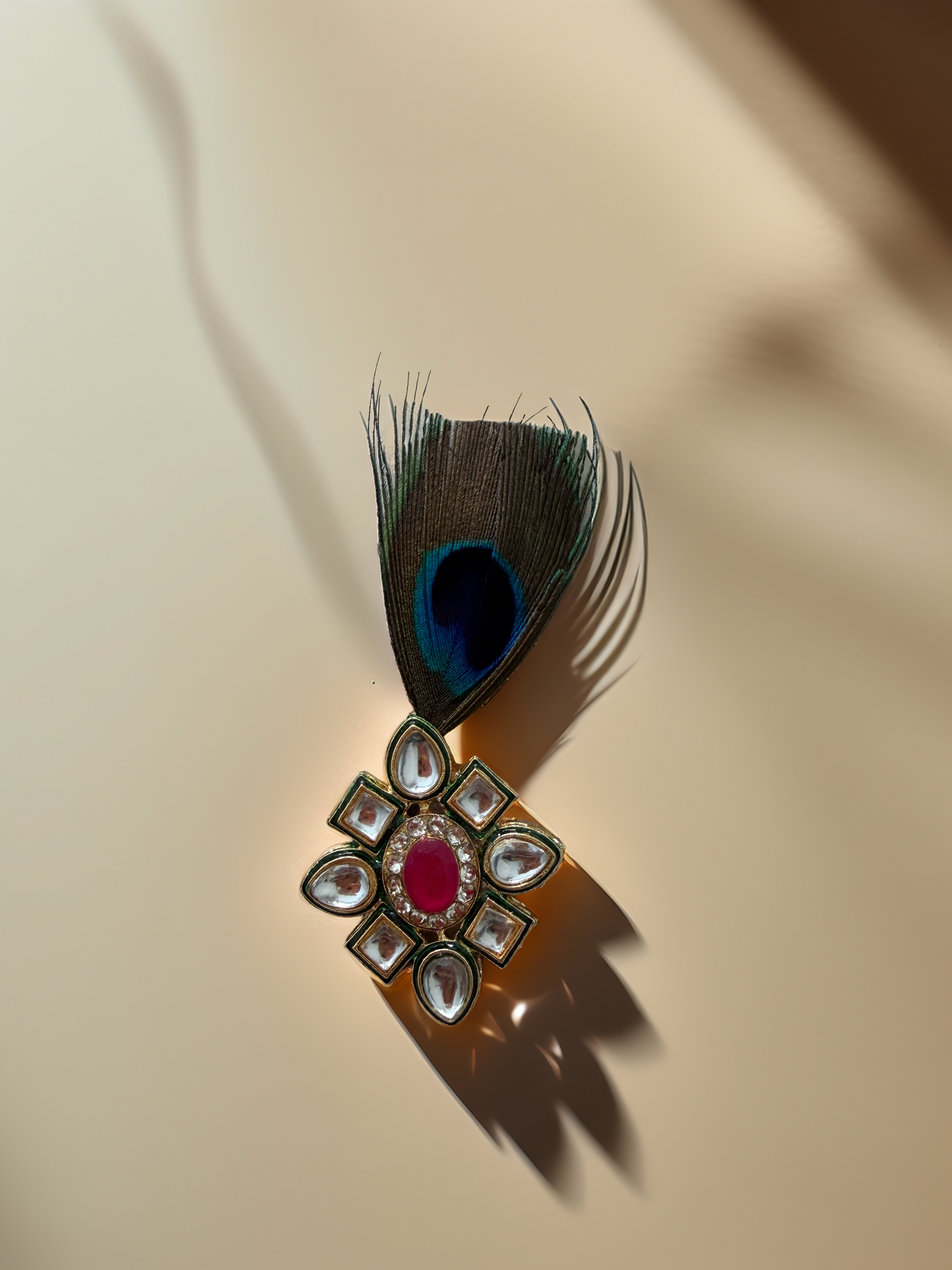 Jeweled brooch with a peacock feather on a beige background