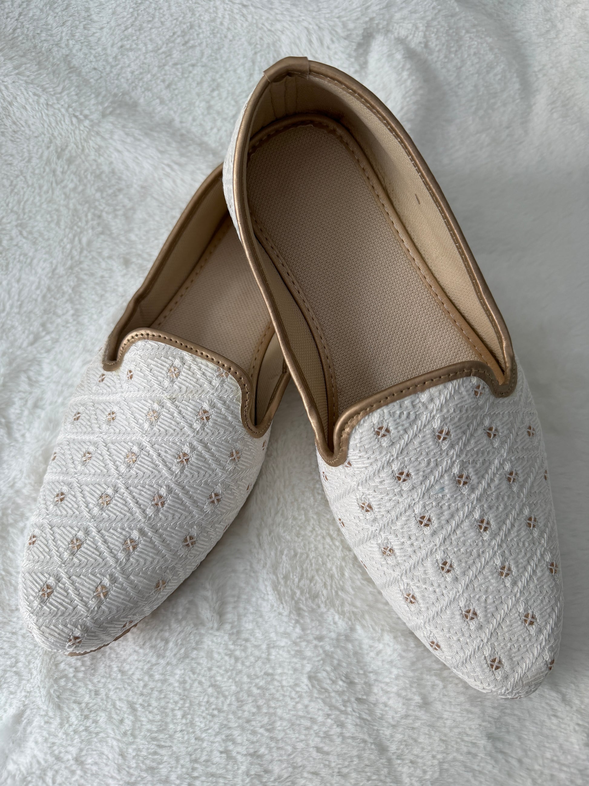 Pair of white slippers with beige interior on a light gray background