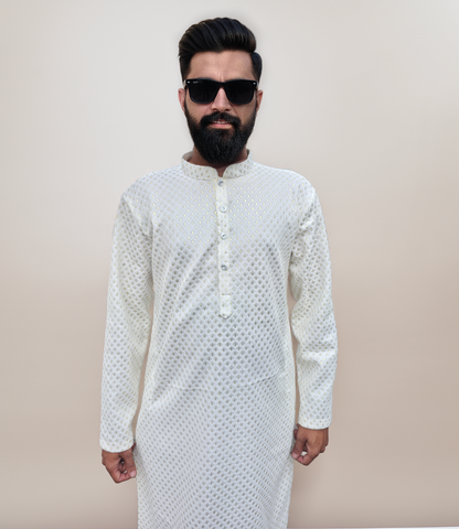 Man wearing a white kurta with a subtle pattern against a beige background