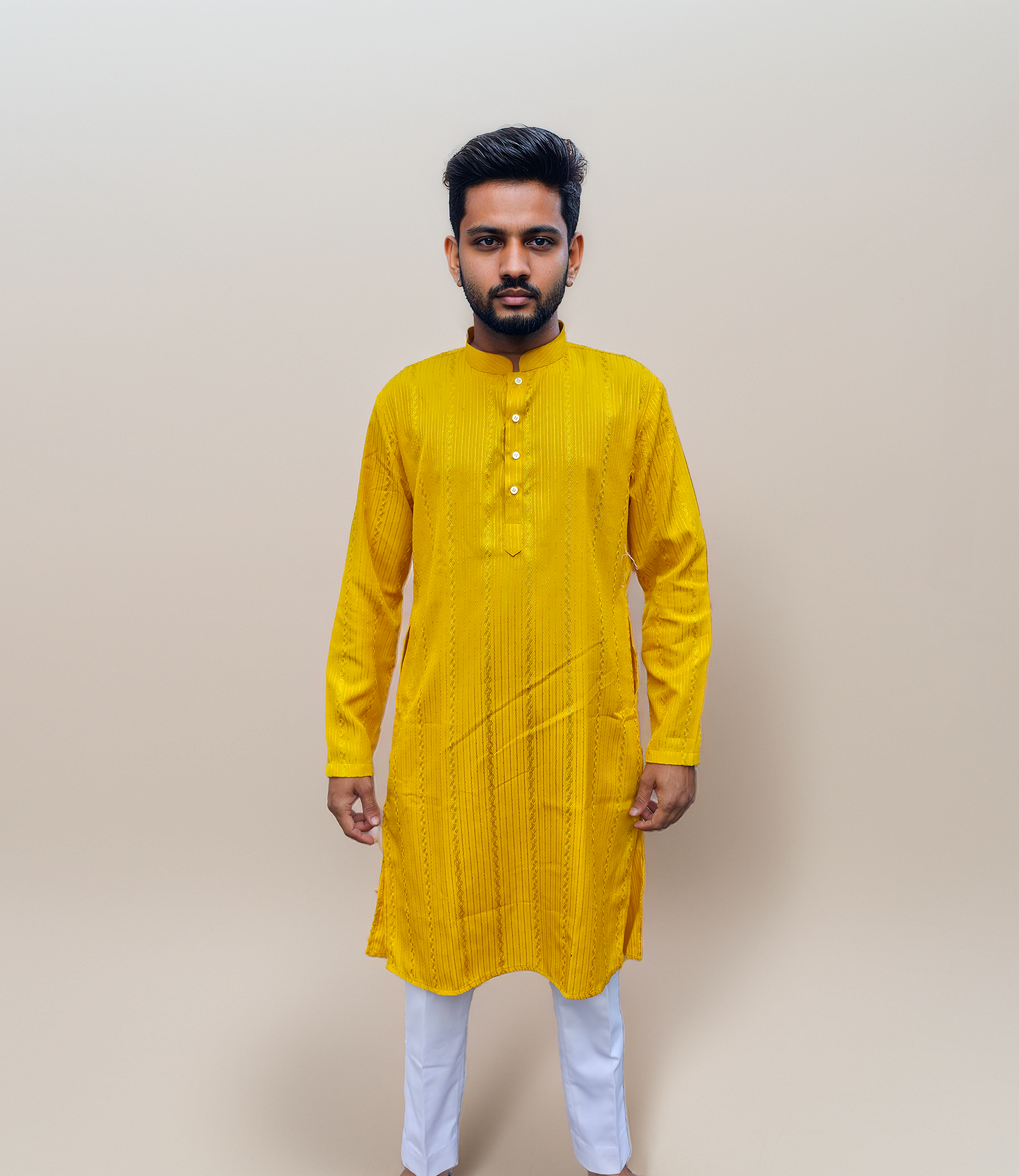 Man wearing a yellow kurta with white pants against a beige background